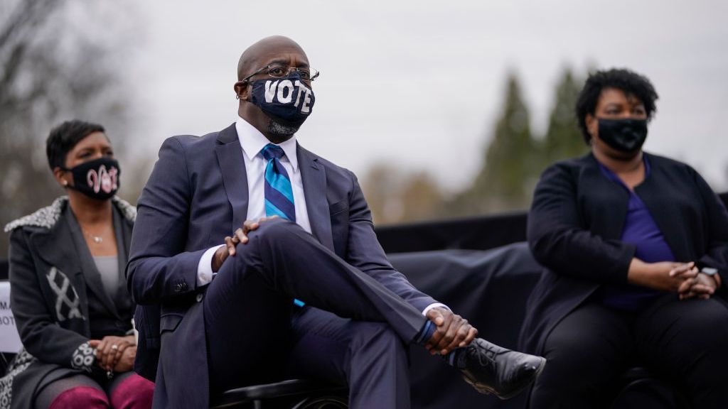 Rev. Ralph Warnock, during his victorious campaign for a U.S. Senate seat to represent Georgia, sits in front of Atlanta Mayor Keisha Lance Bottoms, left, and Georgia Democratic leader Stacey Abrams, right, during a campaign rally in December 2020. (Drew Angerer/Getty Images)