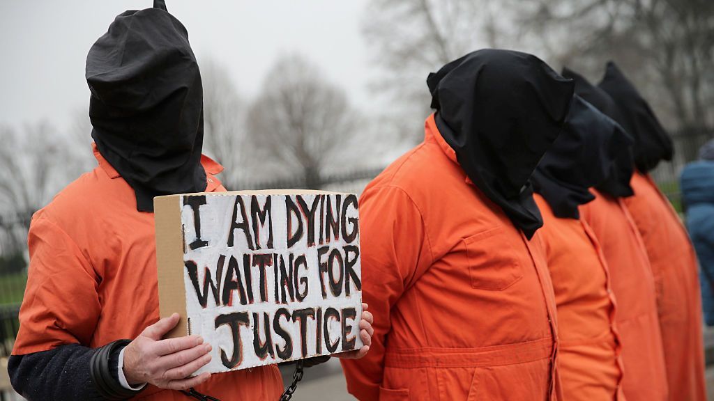 Demonstrators from Witness Against Torture dress in orange jumpsuits and wear black hoods while demanding that then-U.S. President Barack H. Obama close the military prison in Guantanamo, Cuba, outside the White House in January 2016 in Washington, D.C. (Chip Somodevilla/Getty Images)