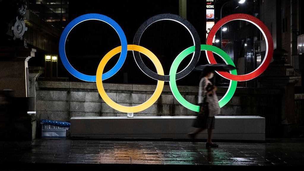 A woman wearing a face mask walks past the Olympic Rings on July 09, 2021 in Tokyo, Japan. (Takashi Aoyama/Getty Images)