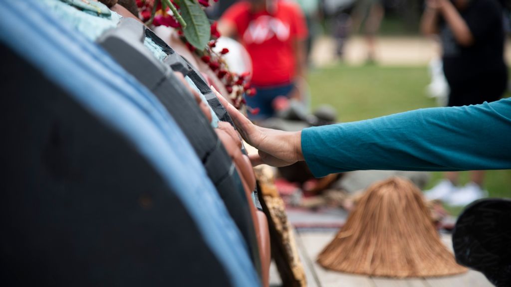 The Lummi Nation transported a 25-foot long totem pole from Washington state to the entrance of the U.S. Capitol.   A woman lays her hand on the totem after a call to pray and empower the 400-year-old cedar. (Zoey Zou/Zenger)